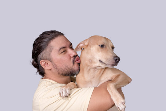 Cute and adorable scene of a man kissing his spoiled mid-sized adult dog he is carrying on his shoulders. Isolated on a white background.