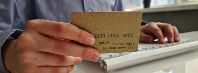 Online payment, a businessman holds credit card in hands and uses laptop for online shopping