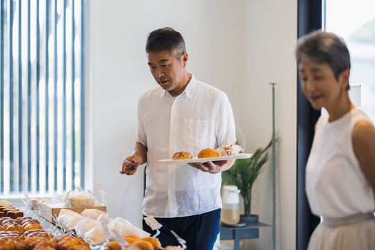 パン屋でパンを選ぶ日本人シニア夫婦