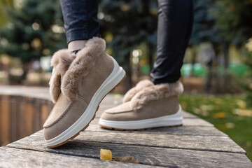 Stylish trendy beige autumn-winter shoes with soft light fur and rhinestones on the gray paving...