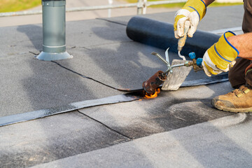 Man Heating and melting bitumen roofing Flat roof installation. - 543377768