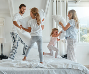 Family, children and pillow fight with parents and girl siblings having fun playing in a bedroom...