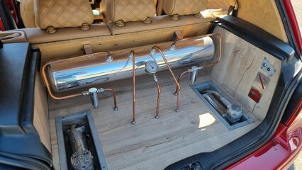 High angle shot of hardline copper tubes and a gauge in a car trunk
