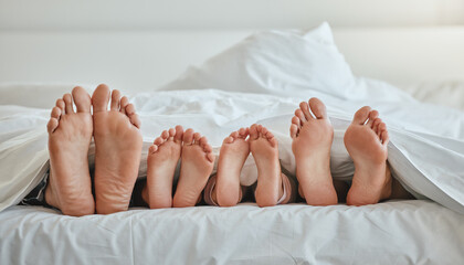 Morning, feet and family sleeping in bedroom for weekend, holiday or nap leisure in house. Relax, mother and dad with young children resting in bed with blanket in family home together.