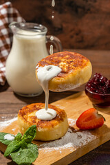 Cottage cheese syrniki poured with creamy sauce, food levitation, falling syrniki, sauce drops on cottage cheese syrniki, wooden table