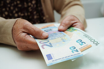 Retired elderly woman holding Euro banknotes money and worry about monthly expenses and treatment fee payment.