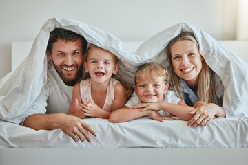 Love, parents and kids under blanket, happy and laugh together for fun, smile and joy. Portrait, family, and have quality time on vacation, holiday and bonding in bedroom for the weekend and cheerful