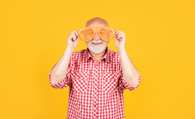 smiling old man in checkered shirt with party glasses on yellow background