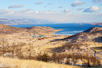 View of the coast of the Small Sea, Kurkut Bay, tourist camps and wooden hotel houses. Lake Baikal in early December.