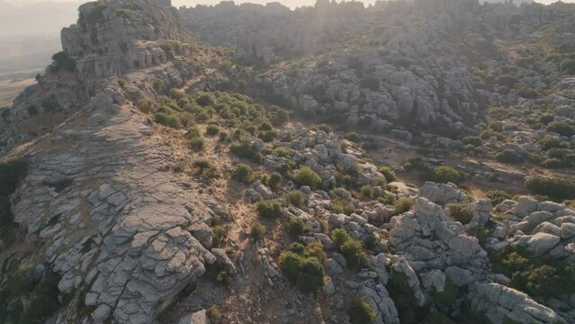 Aerial drone forward moving shot over eroded rocky formation mountain tops in Torcal de Antequera seen from above in Spain during evening time.