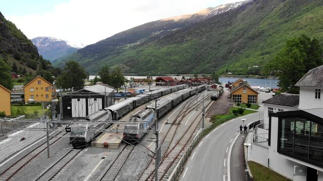 Aerial: train by a river entering Fl&aring;m station