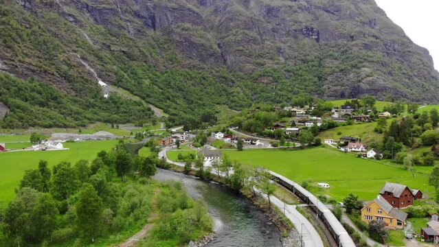 Aerial: Fl&aring;m train going through a valley among green meadows and by a river