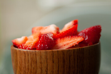 Pieces of fresh peeled strawberries in a wooden bowl