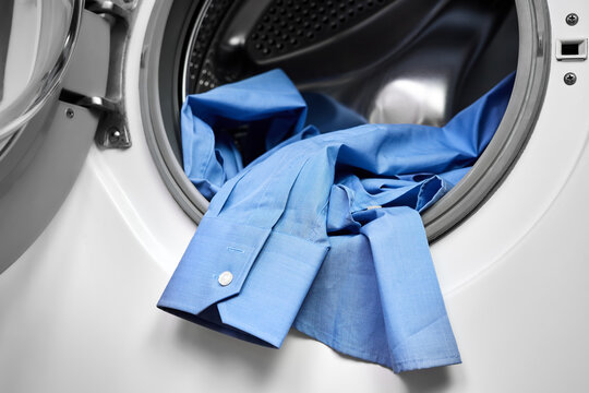 Close-up of an open door in washing machine with dirty shirts inside - Powered by Adobe