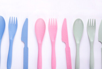 Cutlery set of pastel colors made of wheat straw in a row on white background. Reusable utensils. School lunch concept