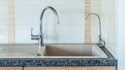Modern interior of kitchen in apartment. Close-up of granite sink. Two water taps. Faucet for...