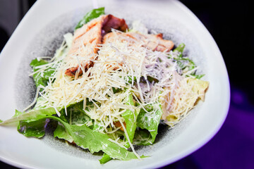 A plate of Caesar salad with chicken breast and parmesan