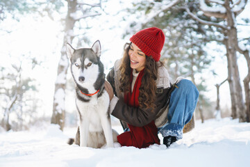 Young woman walking her dog in the winter and both explore the snow together in playful mood. Friendship, pet and human.