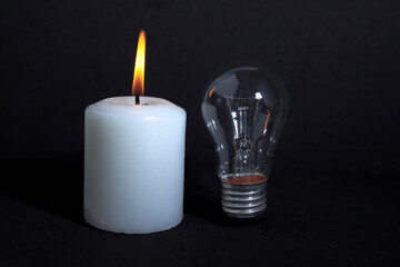 Burning candle and lightbulb on dark background