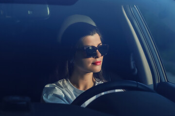 Young woman in sunglasses driving a car