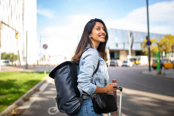 Side of smiling travel woman with bags standing on city street