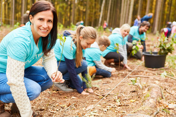 Gruppe freiwilliger Helfer und Kinder beim Baum pflanzen