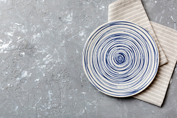 Top view on colored background empty round blue plate on tablecloth for food. Empty dish on napkin with space for your design