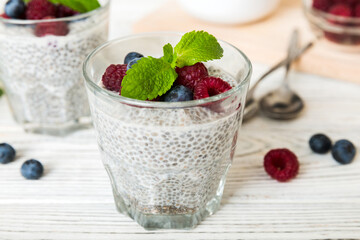 Healthy breakfast or morning with chia seeds vanilla pudding raspberry and blueberry berries on table background, vegetarian food, diet and health concept. Chia pudding with raspberry and blueberry