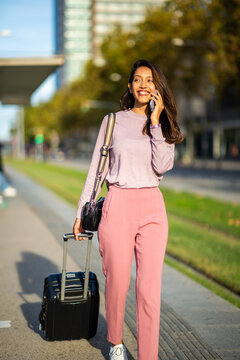 young travel woman walking and talking with cellphone and luggage