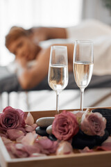 Champagne, massage and couple relax together for a anniversary, love and calm spa experience. Wellness, alcohol with flowers and luxury physical therapy activity of man and woman for romance and rest