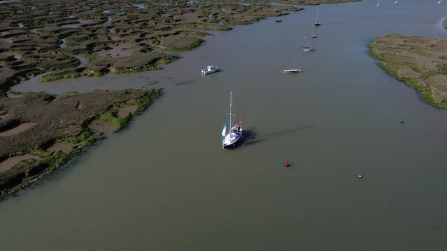 Sailboat on Blackwater River by Swampy Marshes of Tollesbury Marina, Essex, UK - Aerial