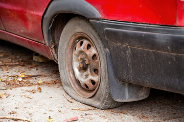 A flat tyre on a car. Flat car tire close up, punctured wheel. Red car with a broken tire