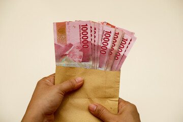 woman's hand showing Indonesian rupiah.  hundred thousand bills in an envelope.  the concept of...