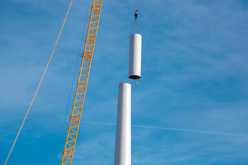 Building and assembling a construction windturbine by crane. Farmland with construction work at the...
