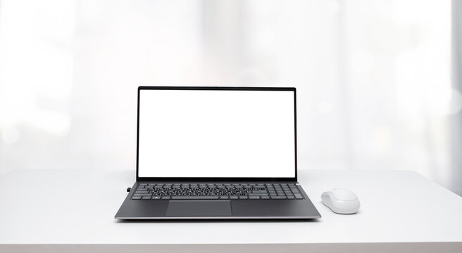 An open laptop with a white screen on a white wooden table, the background is blurred.