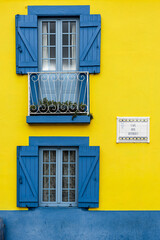 Fototapeta na wymiar yellow facade and windows with blue shutters
