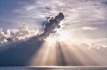 Aerial view of sea under cloudy sky with shining rays