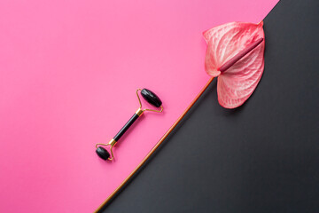 Black gua sha roller, Anthurium on pink and black background