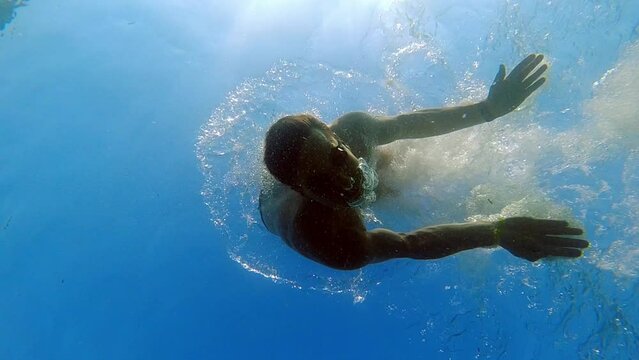 Man Diving and Looking at Camera seen from Underneath Underwater Slow Motion