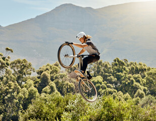 Sport, action and biker doing jump in air with mountain bike for extreme sports, adrenaline and...