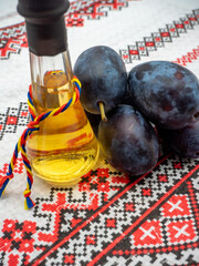 romanian plum brandy known as tuica or tzuica in a glass known as tzoi or toi and heap of ripe plums