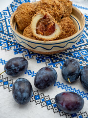 sweet plum dumplings made of leavened dough and fresh plums on clay bowl and plums aside