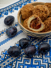 sweet plum dumplings made of leavened dough and fresh plums on clay bowl and plums aside