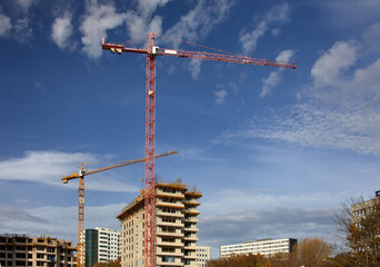Budowa apartamentowca w Katowicach dźwigi budowlane i elewacja podczas budowy na tle błękitnego nieba - obrazy, fototapety, plakaty