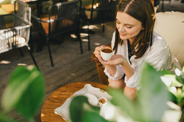 Woman enjoying traditional Turkish coffee sitting by wooden table.