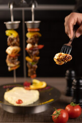 Tower of shish kebab skewers on cast iron . Black background. Side view.