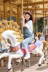 Asian girl playing on the merry-go-round at an amusement park