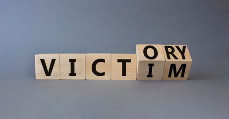 Victory vs Victim symbol. Wooden cubes with words Victory and Victim. Beautiful grey background. Psychology and concept. Copy space