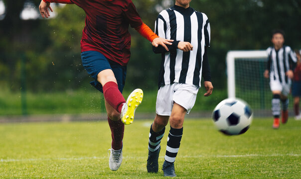 Teenage boys kicking football. Two player in soccer duel on grass pitch. Soccer forward shoot a ball. Defensive player in blurred background