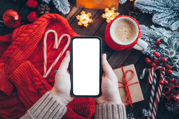Phone in hands with isolated place for text in Christmas atmosphere